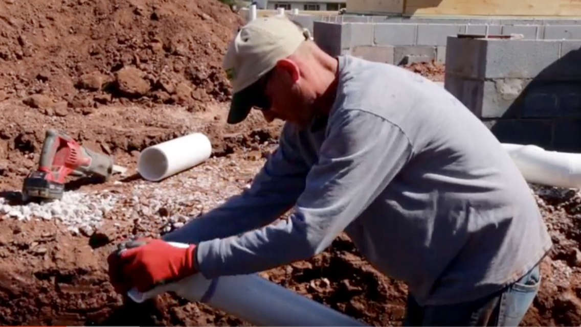 placing pvc plumbing pipes in a trench by a new home